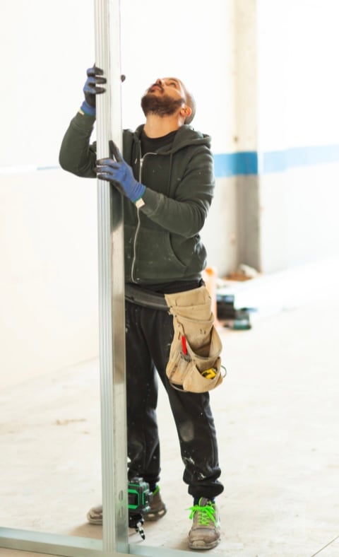 Man building a temporary wall to divide a room.