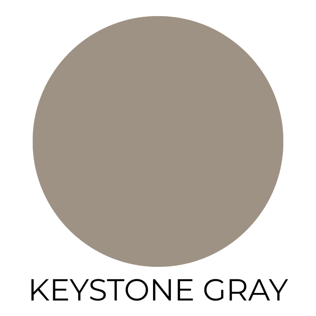 A digital paint swatch labeled “Keystone Gray” by Sherwin-Williams. The image displays a large circle filled with a medium taupe-gray color that has warm, earthy undertones. The background is white, and the name “KEYSTONE GRAY” is centered below the circle in clean, black, all-caps sans-serif text.
