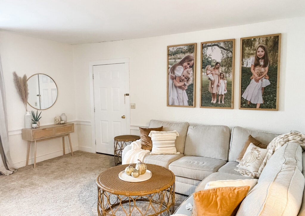 Neutral-toned living room with light beige walls and furniture, perfect example of how light paint colors make a small space feel bigger. Includes soft lighting, woven decor accents, and personal photo gallery above the couch.