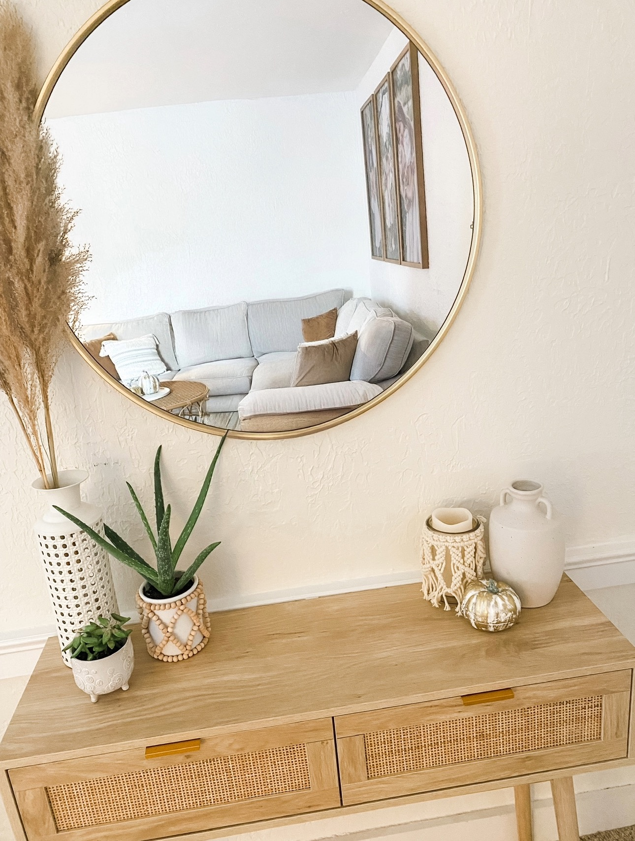 Round wall mirror reflecting a bright neutral living room, showing how mirrors can make a small space feel larger. Styled with minimal decor and natural wood tones for an open, airy look.