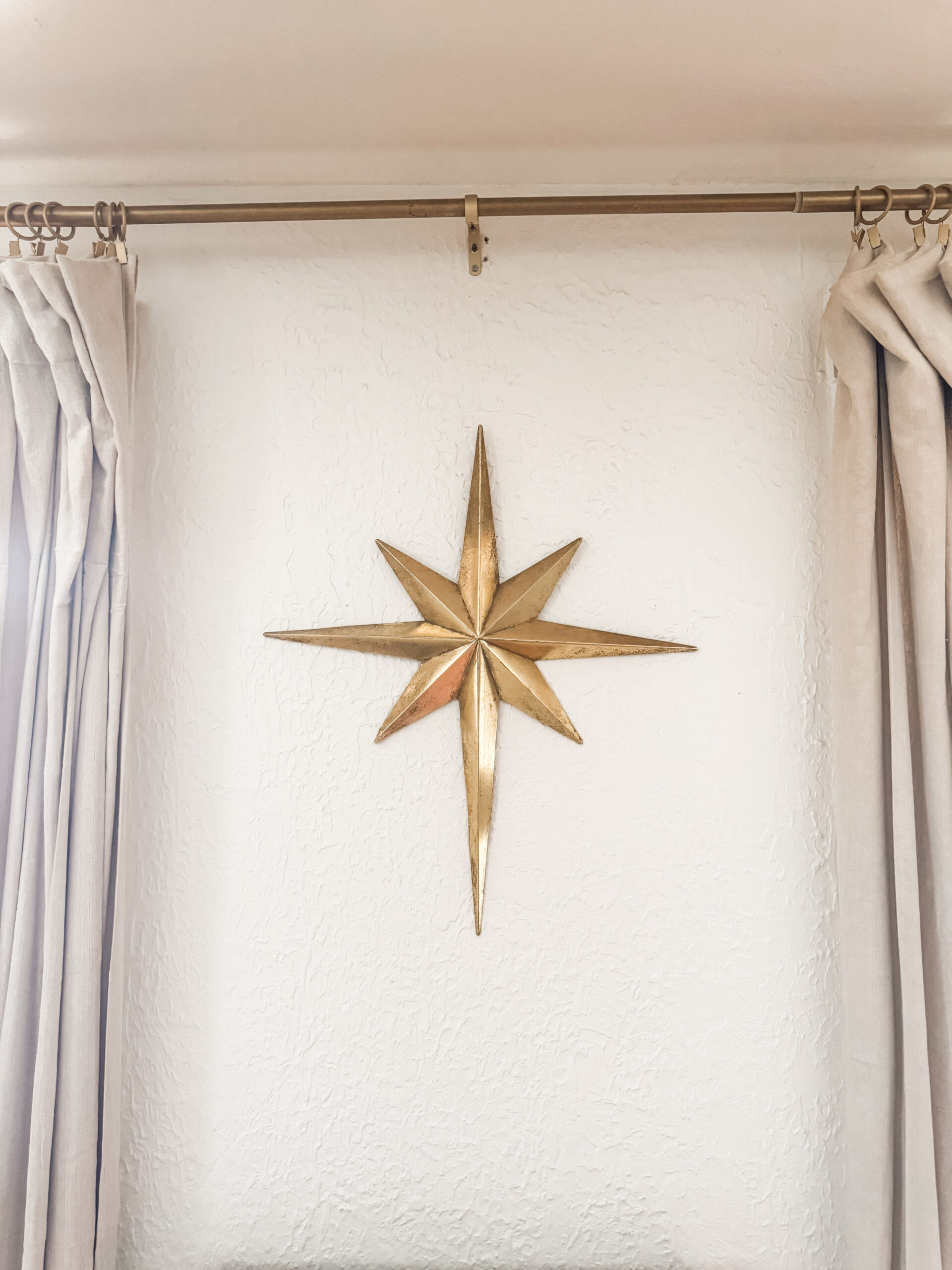 Large gold star wall accent adding a bold but minimal touch to neutral Christmas living room decor.