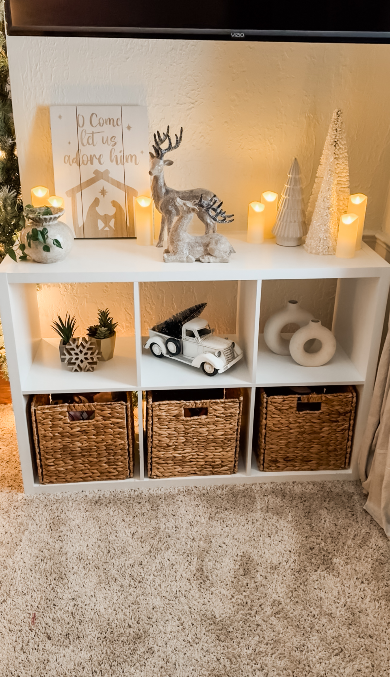 Neutral Christmas shelf decor with candles, greenery, and warm textures for a cozy winter glow.