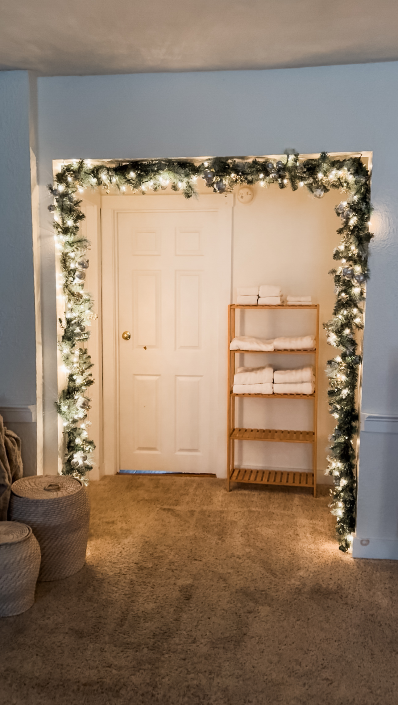 Pre-lit neutral Christmas garland framing a wide doorway with warm, cozy lighting.