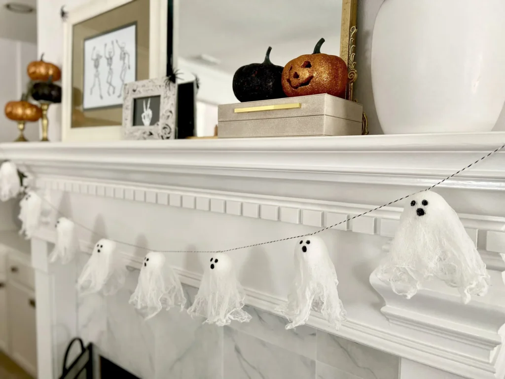 DIY Halloween craft ghost garland hanging from a mantle.