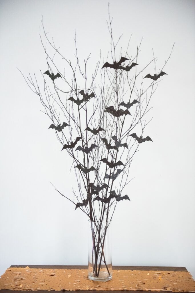 DIY Halloween centerpiece with twigs and bats in a vase.