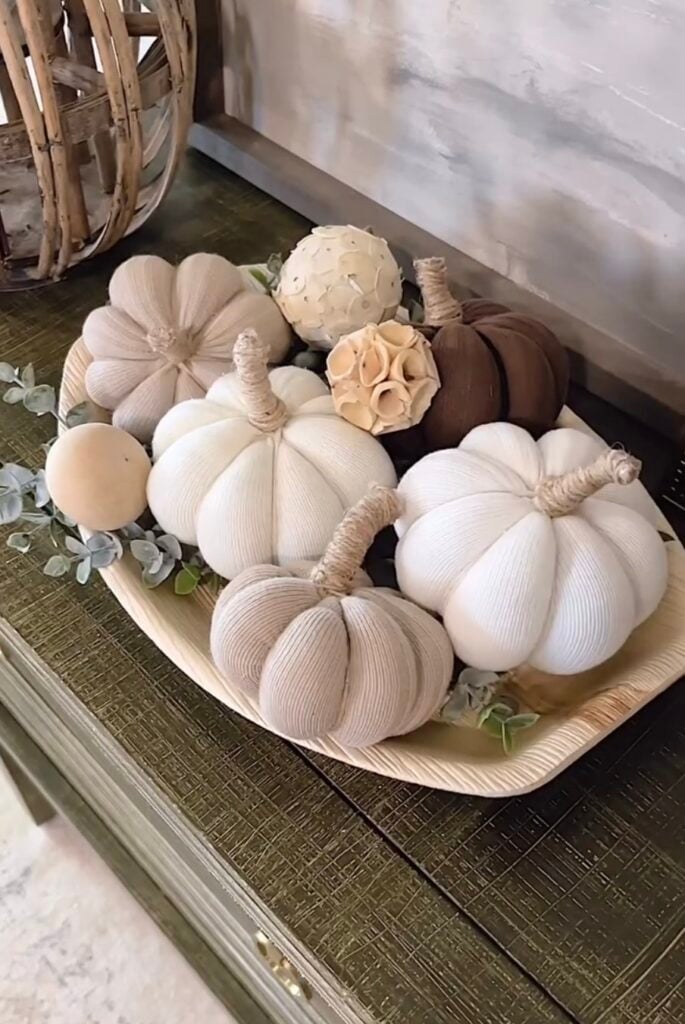 Neutral fabric pumpkins arranged on a wooden tray with eucalyptus stems and decorative accents, making a beautiful easy DIY fall decor centerpiece for a console table.