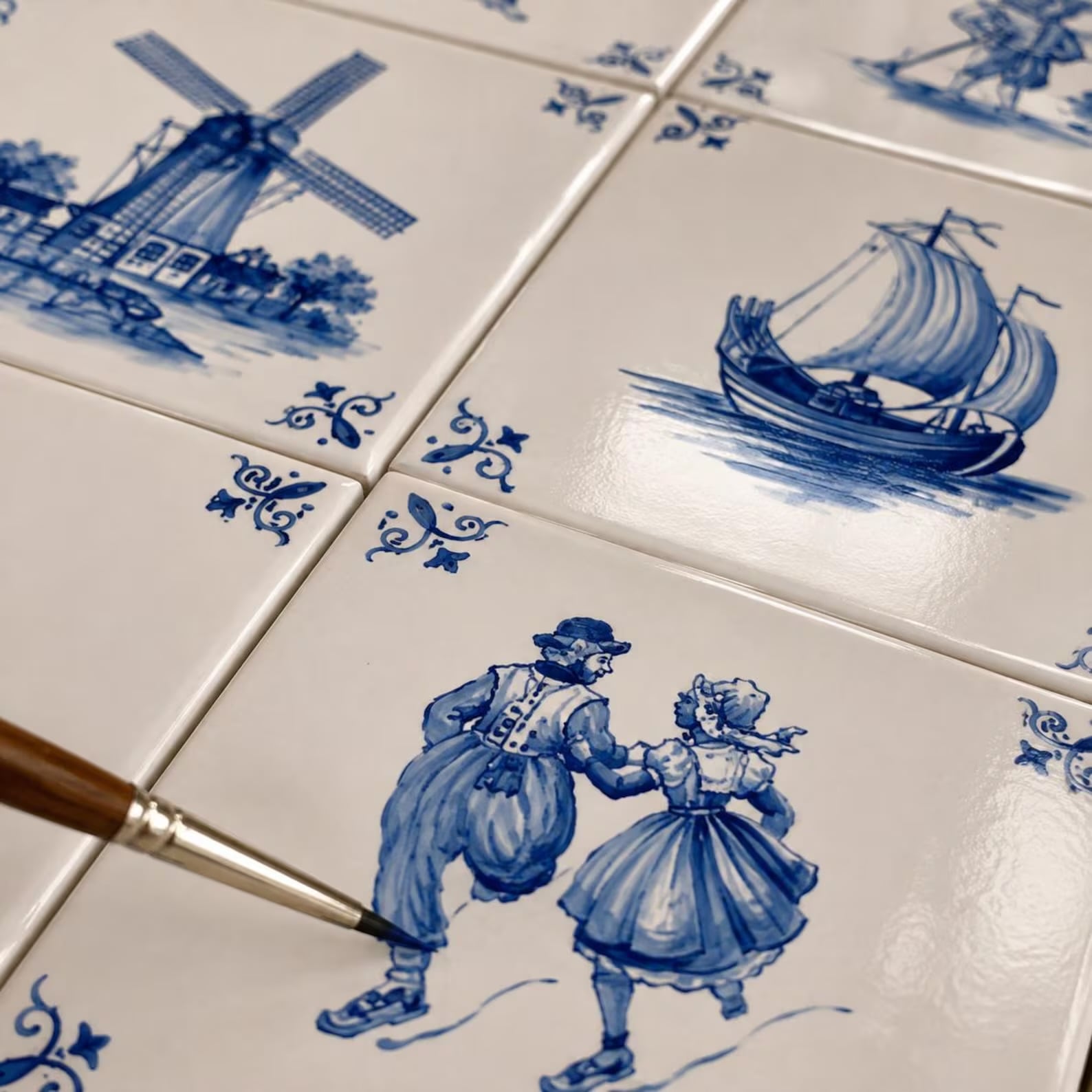 Popular kitchen backsplash idea featuring Delft-inspired blue and white tiles with hand-painted Dutch scenes, including windmills, sailboats, and traditional figures.
