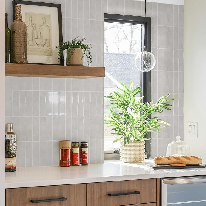 Popular kitchen backsplash idea featuring vertically stacked light gray tiles extending to the ceiling, paired with warm wood cabinets, black hardware, and floating wood shelves.
