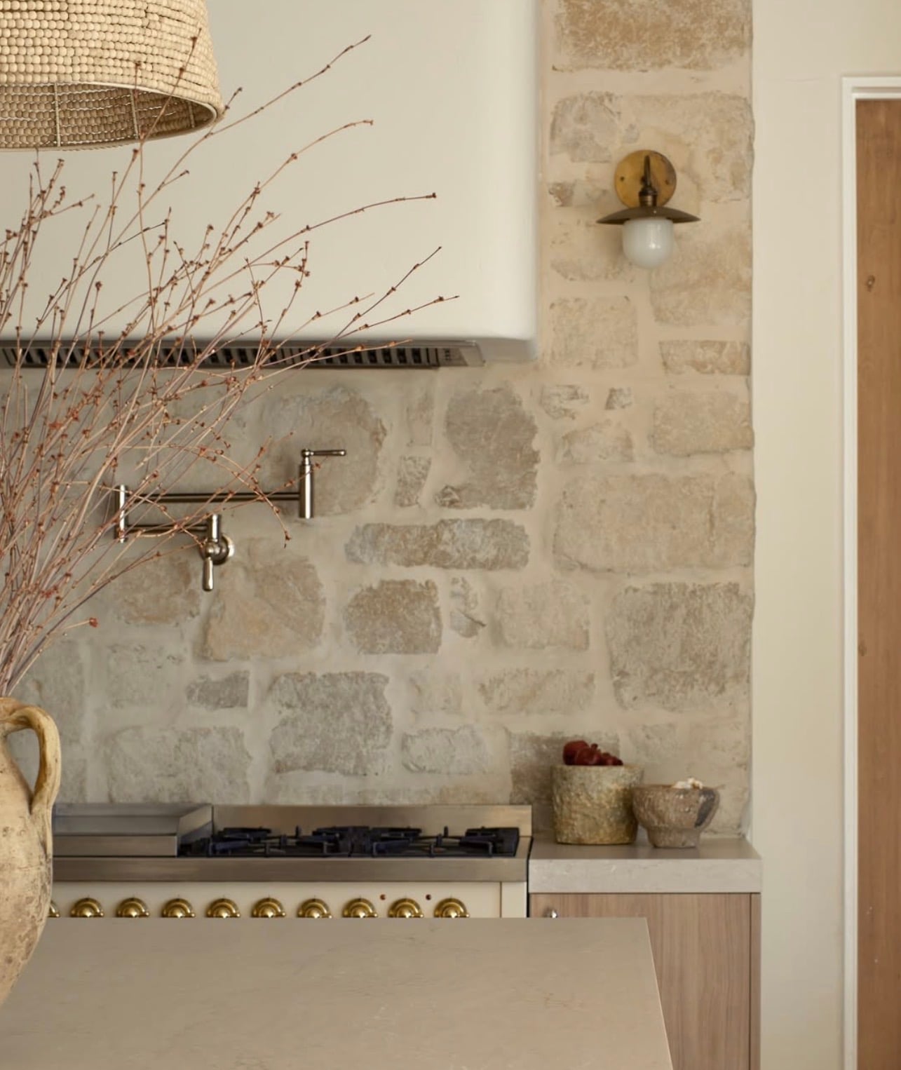 Popular kitchen backsplash idea featuring a rustic natural stone backsplash in warm cream and beige tones, paired with light wood cabinetry and neutral countertops.