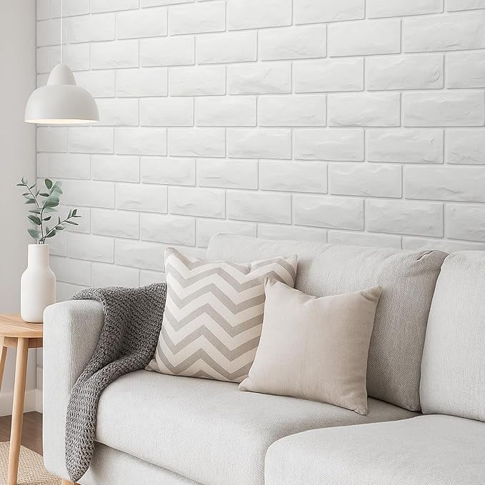 White peel and stick brick accent wall behind a neutral sofa with beige pillows, a gray throw blanket and simple modern decor.