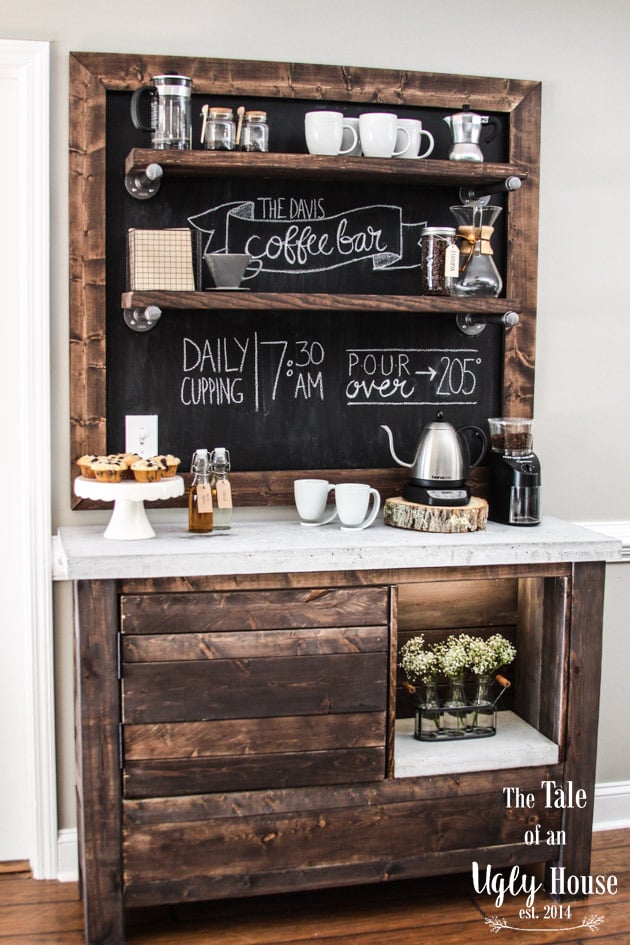 DIY rustic kitchen coffee bar with a custom concrete countertop, dark stained wood cabinetry, open shelving, and a large framed chalkboard with handwritten coffee shop lettering.